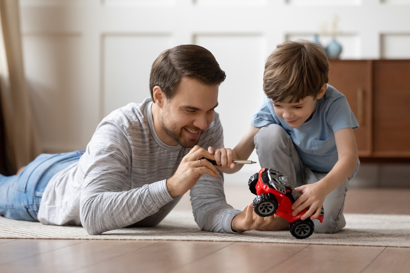 Happy dad play with toy car with small son